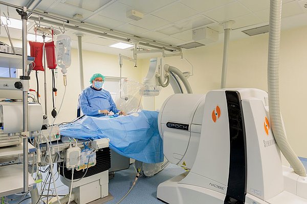 Dr. Hügl führt Herzkatheter-Untersuchung in einem modernen Operationssaal mit medizinischer Ausrüstung durch