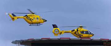 Zwei gelbe ADAC-Helikopter landen auf einer Plattform. Der vordere Helikopter hat das Logo von ADAC Luftrettung.