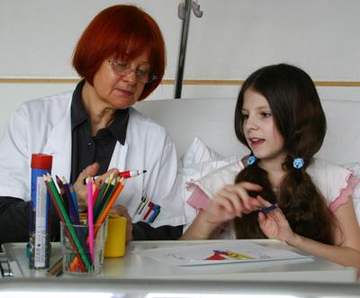 Frau malt mit Kind zusammen im Krankenhaus